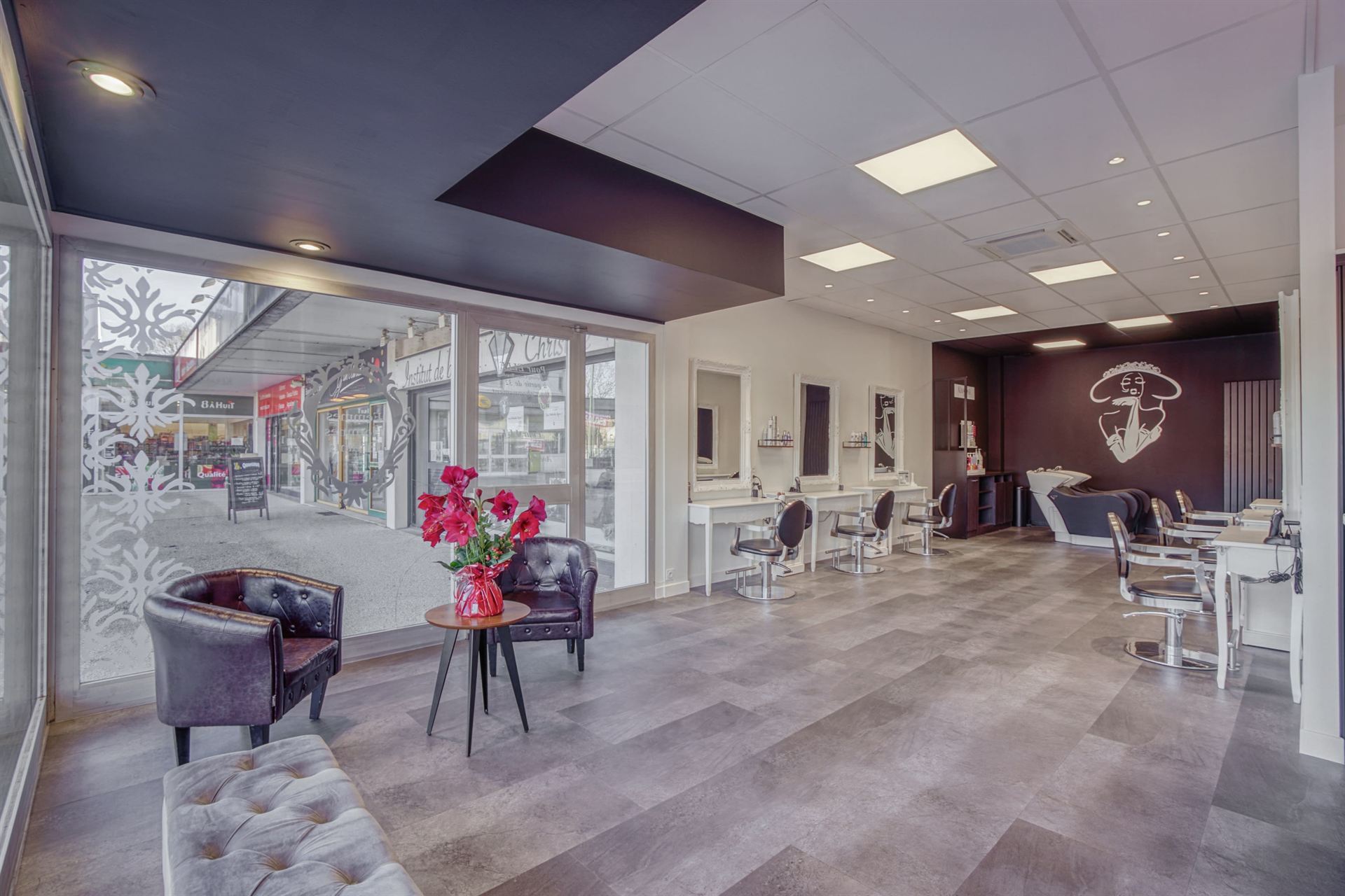 Espace d'attente du salon avec fauteuils en cuir capitonné et bouquet de fleurs